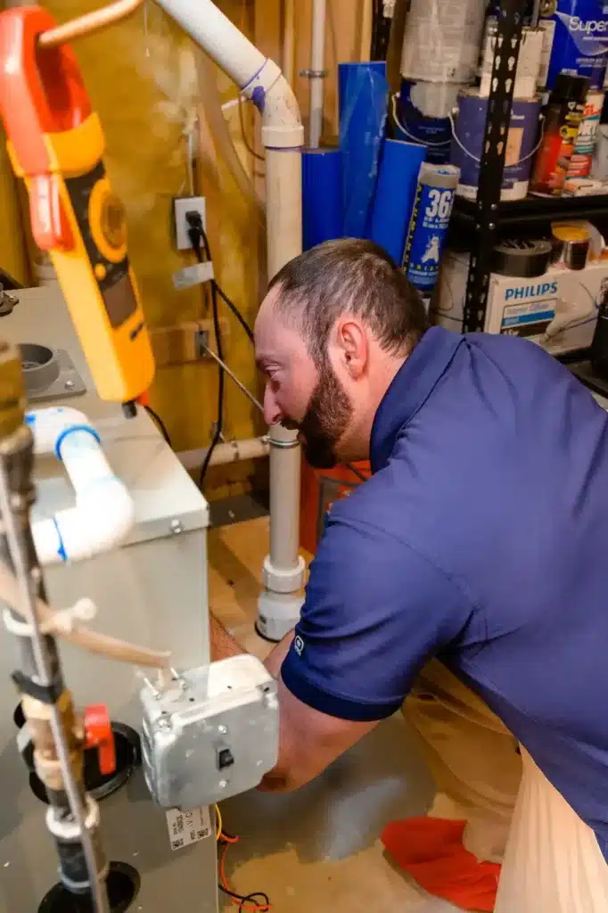 Service technician in a home basement and working on a heater.
