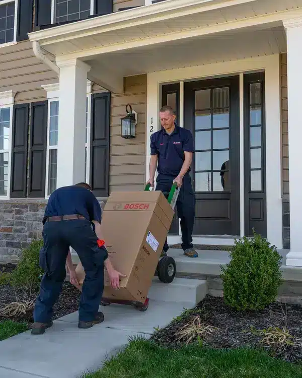 technicians moving hvac unit into house