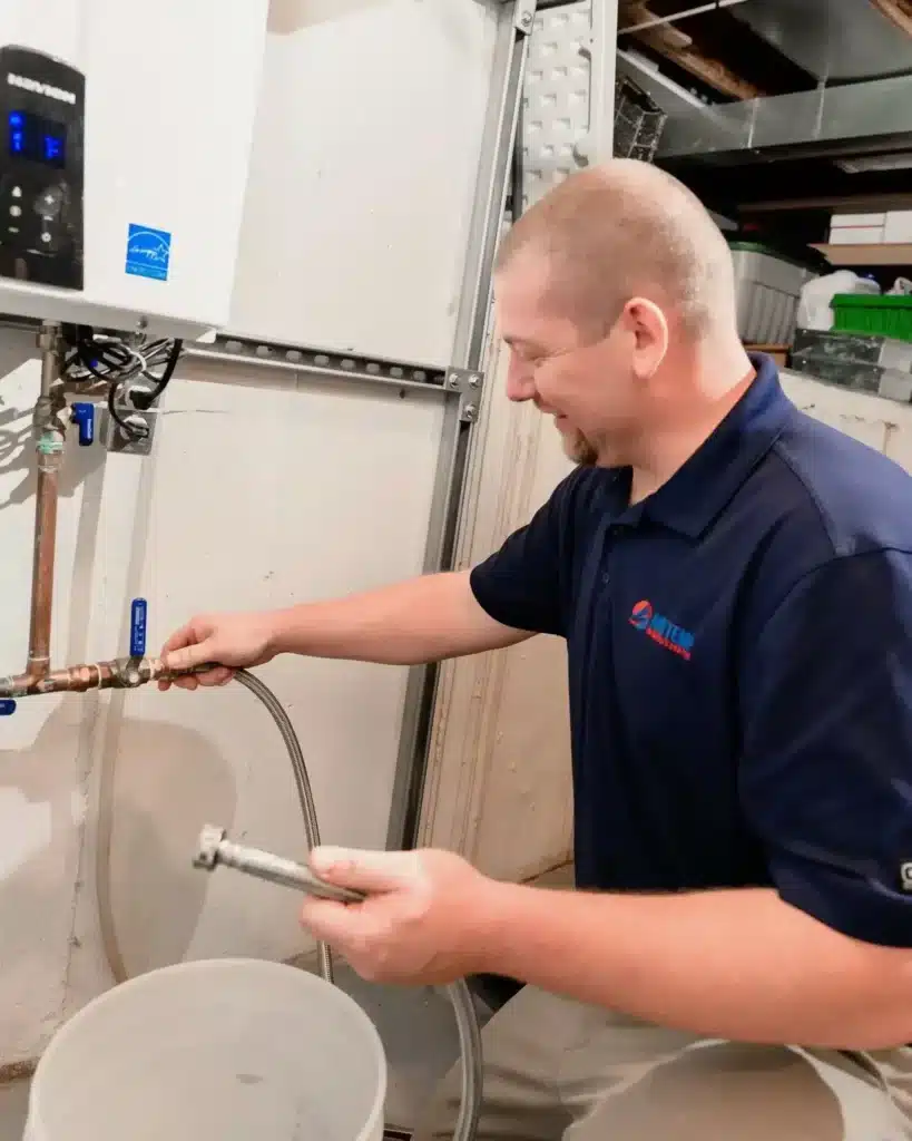 A service technician is in a residential basement working on a tankless water heater.