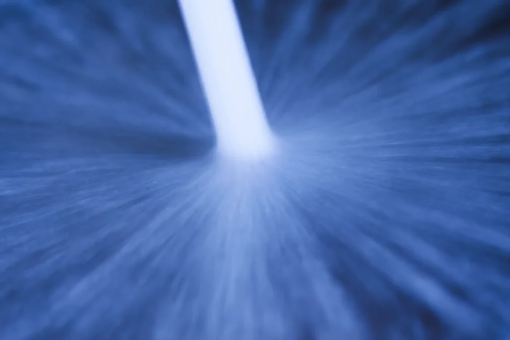 A white vertical beam of light extends from the center of a blue radial blur, evoking the powerful force of Hydro Jetting and creating a dynamic, abstract visual effect.