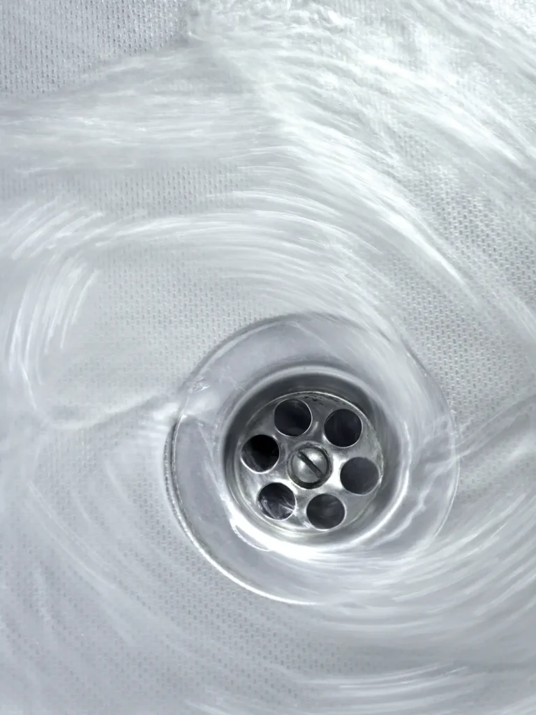 Water swirling around a silver sink drain, creating a visible vortex as it flows down—perfectly illustrating when you might need expert Rooter Service in DE.